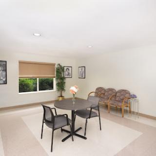 A bright and minimalist dining area featuring a round table and chairs, complemented by natural light from a window.