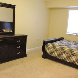 A neatly arranged bedroom with a bed, dresser, and window.