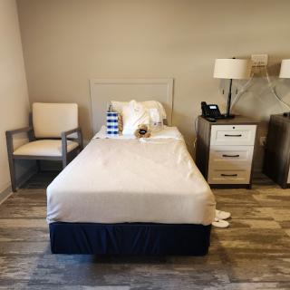 A cozy minimalist bedroom featuring a single bed, a lamp, and a nightstand.