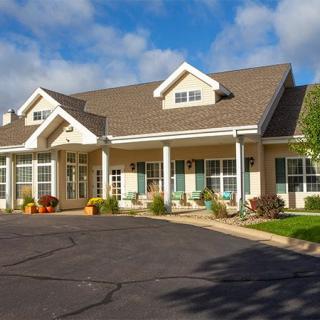 A suburban house with a paved driveway and manicured front yard under a clear blue sky.
