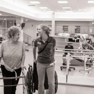 A patient and a healthcare worker engage in a friendly conversation during a rehabilitation session.