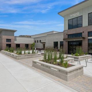 A modern commercial building with landscaped planters under a clear blue sky.