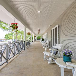 A spacious outdoor porch with white chairs and hanging plants, ideal for relaxation.