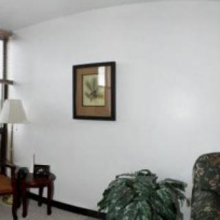 A cozy living room with a lamp, artwork on the wall, and a potted plant.