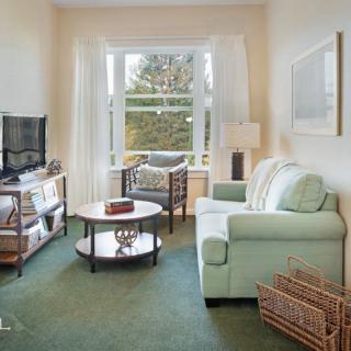 A cozy living room featuring a comfortable sofa, television, and coffee table with a large window offering natural light.