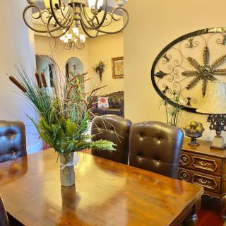 A cozy dining room featuring a wooden table with leather chairs, a decorative plant centerpiece, and an elegant chandelier.