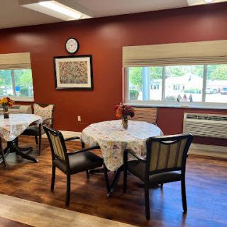 A cozy dining area featuring tables with lace tablecloths, comfortable chairs, and a decorative atmosphere.