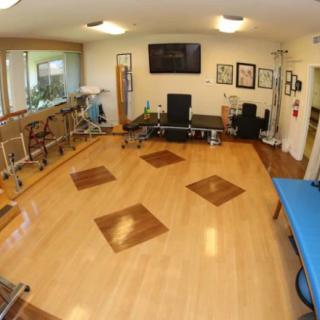 A spacious physical therapy room equipped with various rehabilitation tools and exercise equipment.