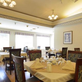 An elegantly set dining area with neatly arranged tables and chairs in a well-lit restaurant interior.