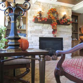 A cozy living room with autumn-themed decorations, featuring a fireplace and a pumpkin on the table.