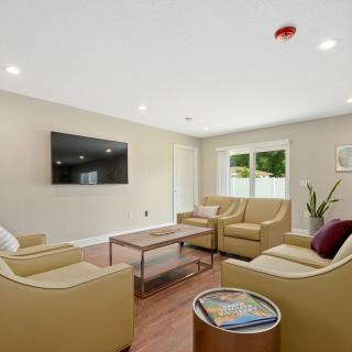 A modern living room with beige sofas, a coffee table, and a wall-mounted TV.