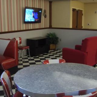 A retro-style diner interior with red seating and a checkerboard floor.