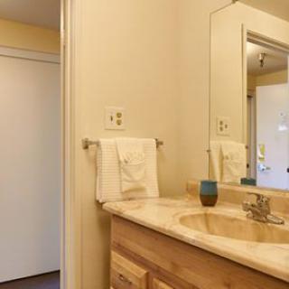 A clean and simple bathroom with a wooden vanity, mirror, and towel rack.