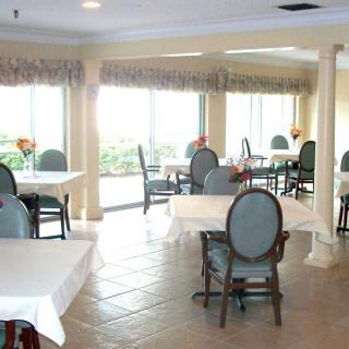 An empty dining area with tables and chairs, well-lit by natural light.