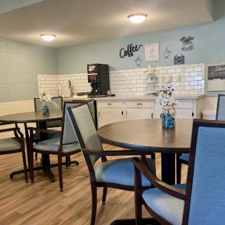A cozy dining area featuring tables, chairs, and a coffee station in a modern kitchenette.