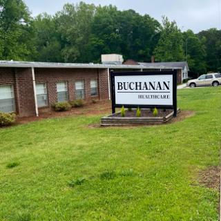 View of the Buchanan sign in front of a building, surrounded by grass and trees.