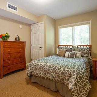 A cozy bedroom with a wooden dresser and a patterned bedspread.