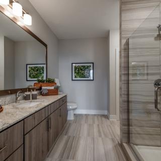 A modern bathroom featuring a double sink vanity, large mirror, and a glass-enclosed shower.