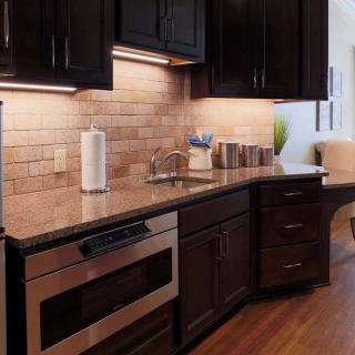A modern kitchen with dark wood cabinets, a sleek countertop, and stainless steel appliances.