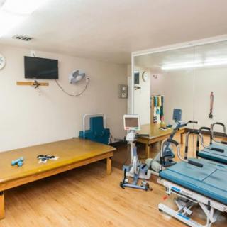 A small exercise room with various gym equipment, including a stationary bike and rehabilitation apparatus.