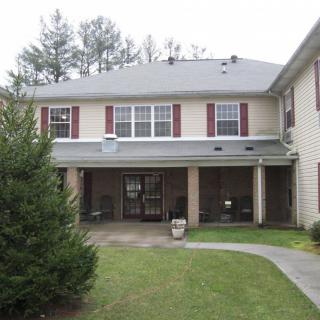 A two-story residential building with a lawn and trees in front.