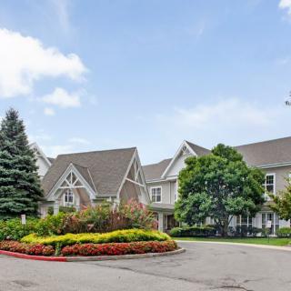 A suburban house with a driveway surrounded by trees and flowers.