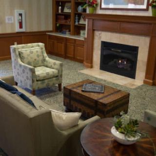 A cozy living room with a fireplace, armchair, couch, and bookshelf.