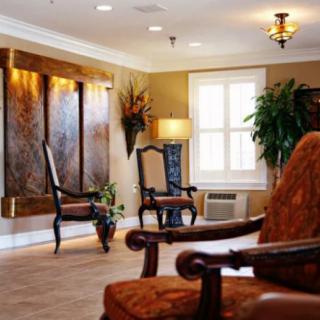 A warmly lit lobby with elegant chairs, artwork, and greenery.