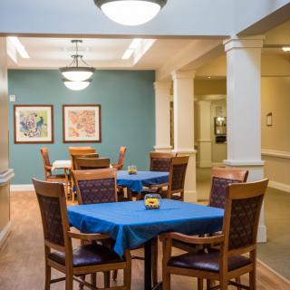 A well-lit dining area with neatly arranged tables and chairs, featuring wall artwork.