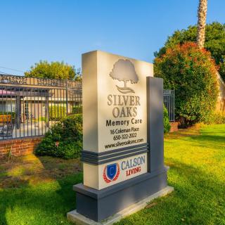 Sign for Silver Oaks Memory Care facility set against a landscaped outdoor area.