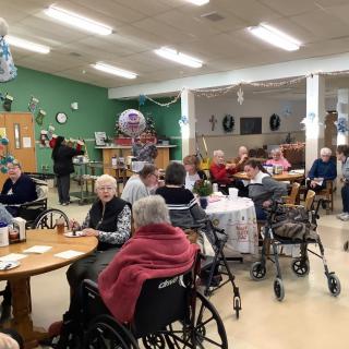 A group of elderly people socializing in a nursing home setting.