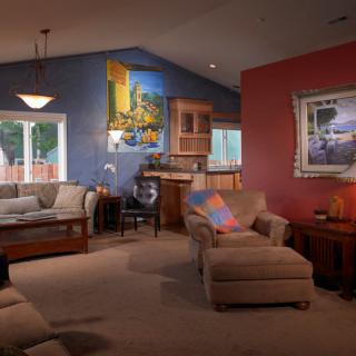 A cozy living room with colorful walls, featuring comfortable seating and various artworks.