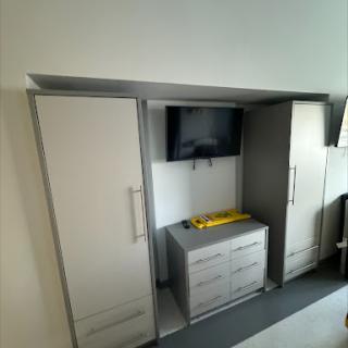 A modern storage unit featuring two wardrobes and a TV mounted in the center.
