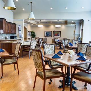 A well-organized dining area with neatly arranged tables and chairs, featuring decorative napkins and elegant lighting.