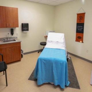 A clean and organized medical examination room with an examination table and cabinets.