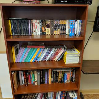 A wooden bookshelf filled with a variety of books and DVDs.