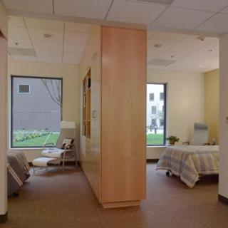 A modern hospital patient room with a bed and seating area.