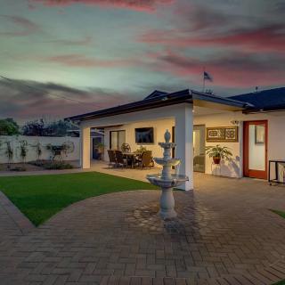 A serene backyard with a patio and fountain at sunset.