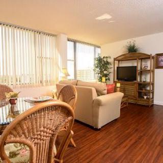 Cozy living room with natural light, featuring a sofa, television, and dining area.