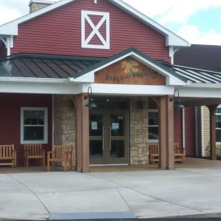A barn-style restaurant entrance with wooden benches and a welcoming facade.