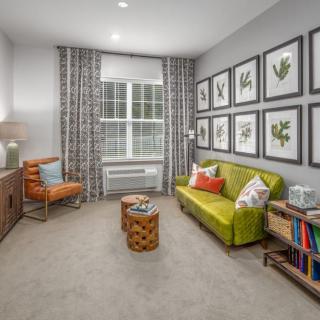 A modern living room with a green sofa, wall art, and a cozy reading corner.