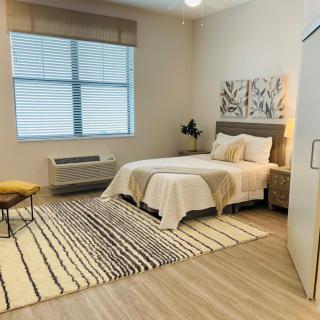 A modern and minimalist bedroom with a cozy bed, decorative rug, and large window.