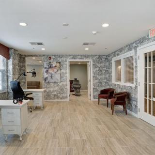 A modern office interior with a desk, chairs, wood flooring, and patterned wallpaper.