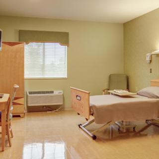 A clean and tidy hospital room with a bed, chair, and window.