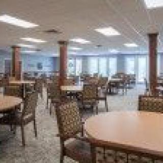 A spacious dining area with multiple tables and chairs, well-lit by ceiling lights.