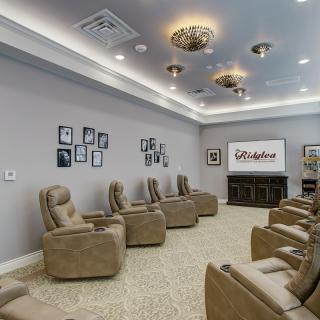 A cozy home theater room with multiple recliner chairs, a large screen, and decorative lighting.