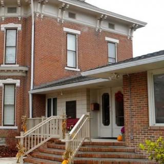 A brick house with a modern extension and steps leading to the entrance.
