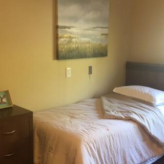 A cozy bedroom with a single bed and wall painting.