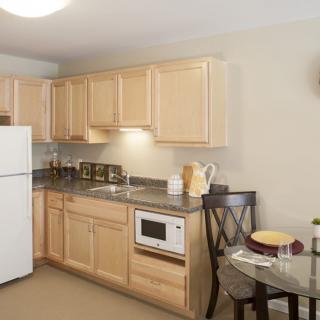 A cozy kitchen with light wood cabinets, a white fridge, and a compact dining area.