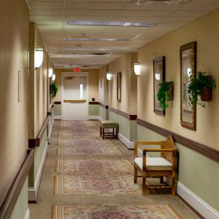 A long, carpeted hallway with chairs and wall decorations.